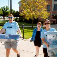 three people moving bins into the honors college